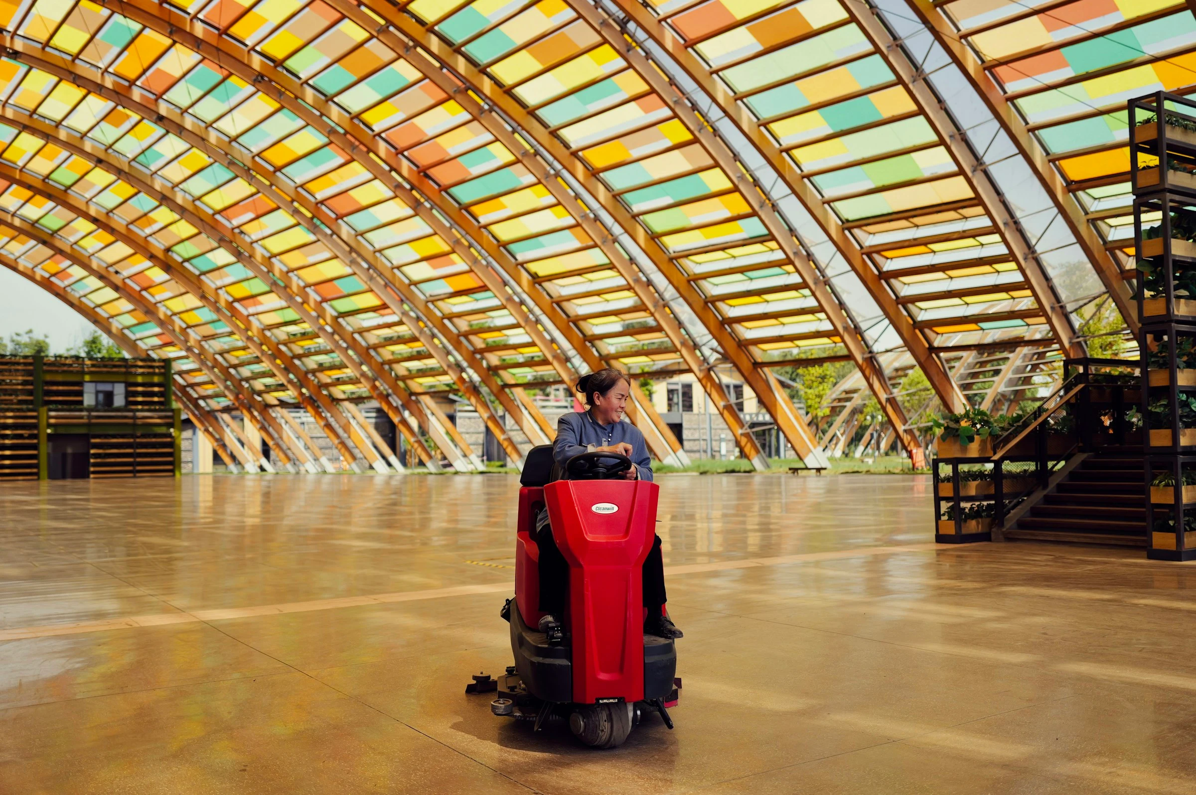 Cleaning operator using a professional ride-on floor scrubber in a large public atrium